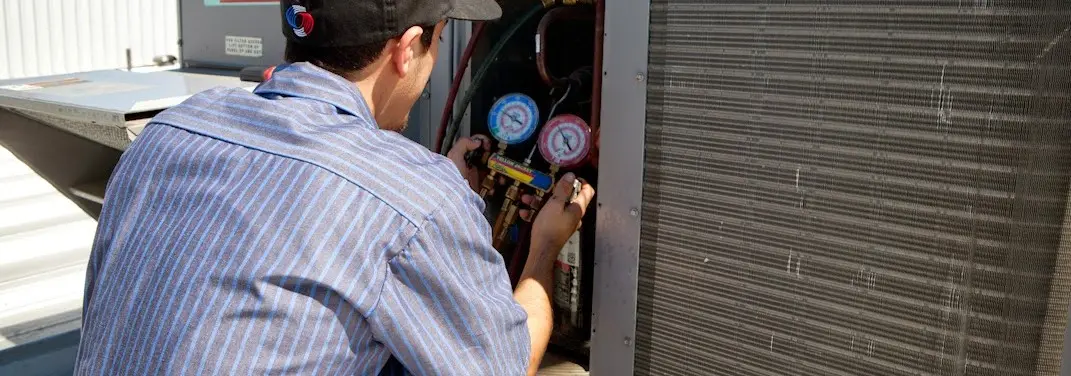 HVAC technician servicing a condenser unit in Sealy