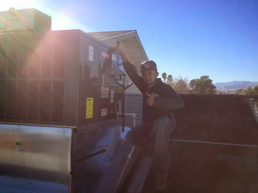 HVAC technician performing Air Duct Repair on a rooftop unit in Sealy